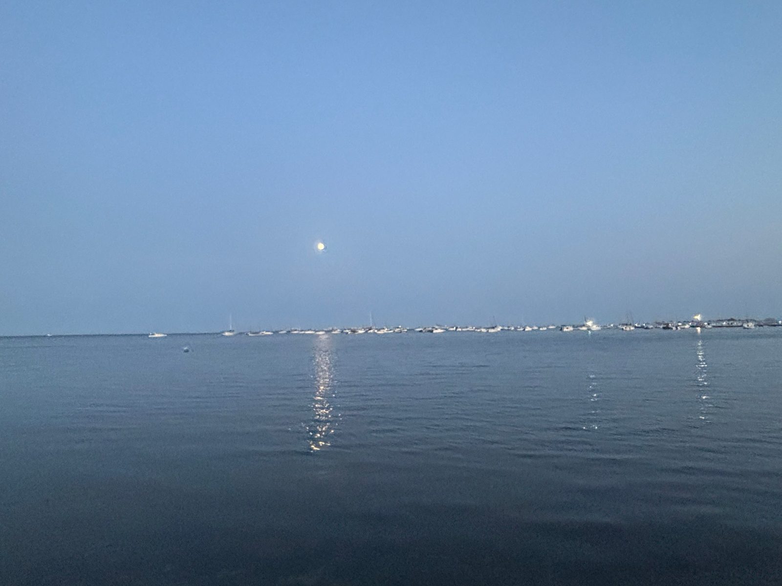 El Mar Menor al anochecer con barcos fondeados y la luna reflejada